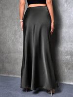 Person wearing a long black skirt against a gray background