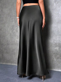 Person wearing a long black skirt against a gray background