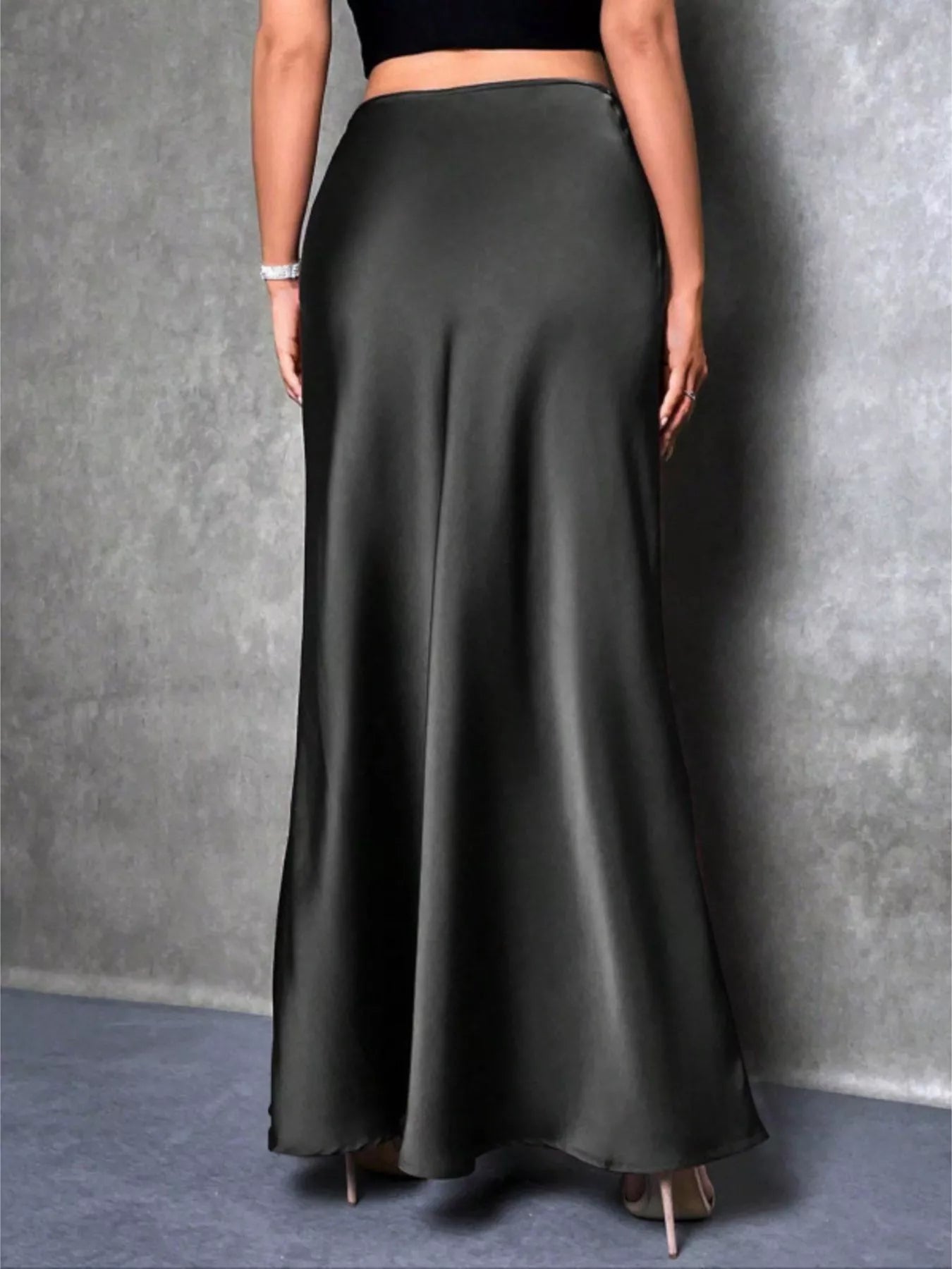 Person wearing a long black skirt against a gray background
