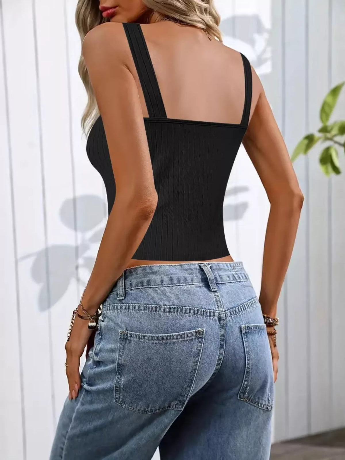 Person wearing a black tank top and blue jeans with a white background