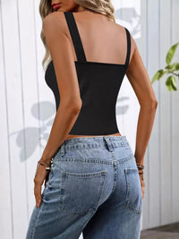 Person wearing a black tank top and blue jeans with a white background