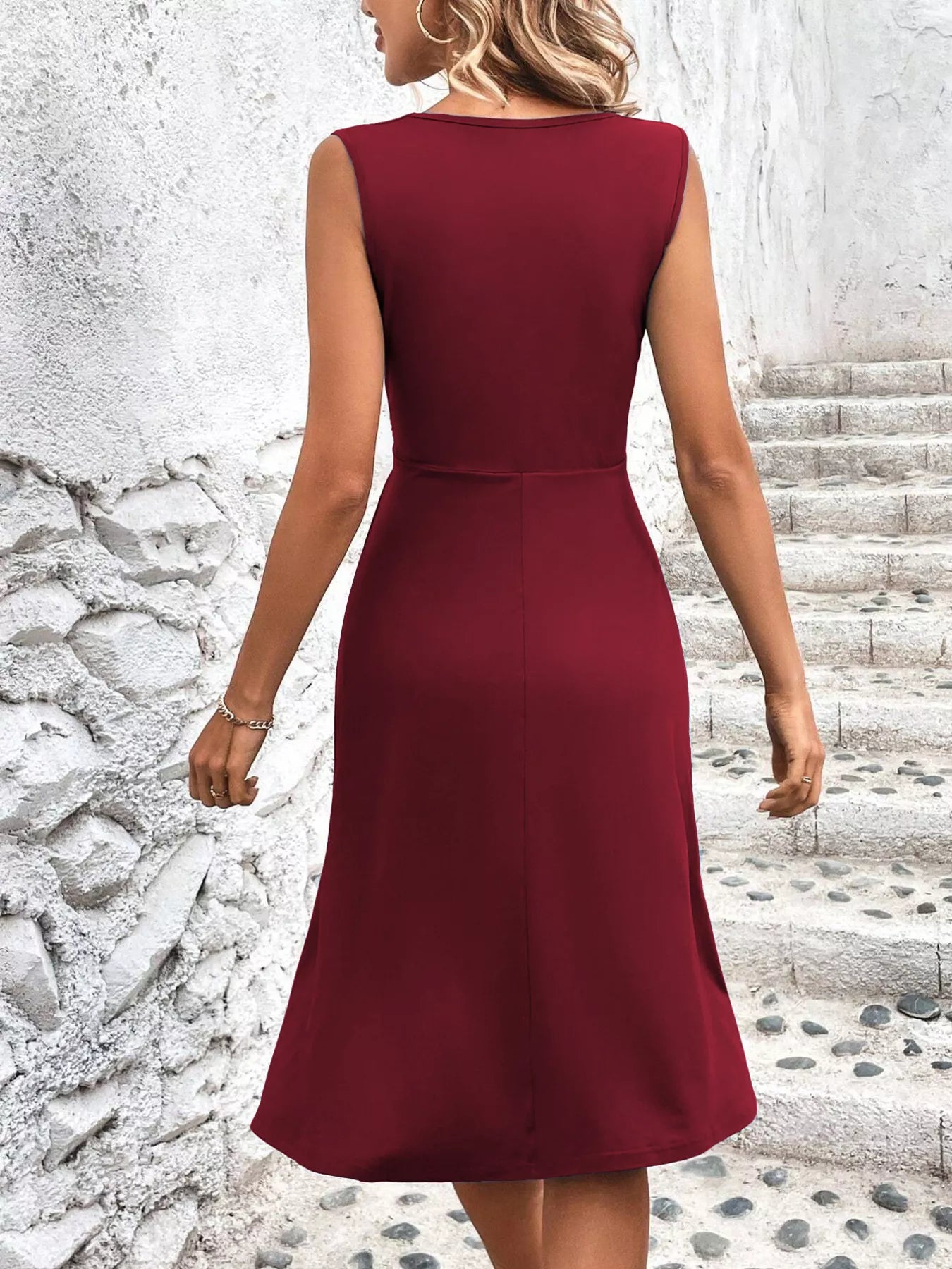 Burgundy dress worn by a person standing on stone steps with a textured wall background