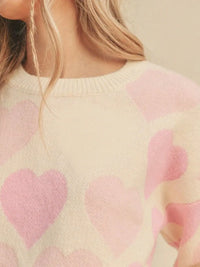 Close-up of a person wearing a sweater with pink heart patterns.