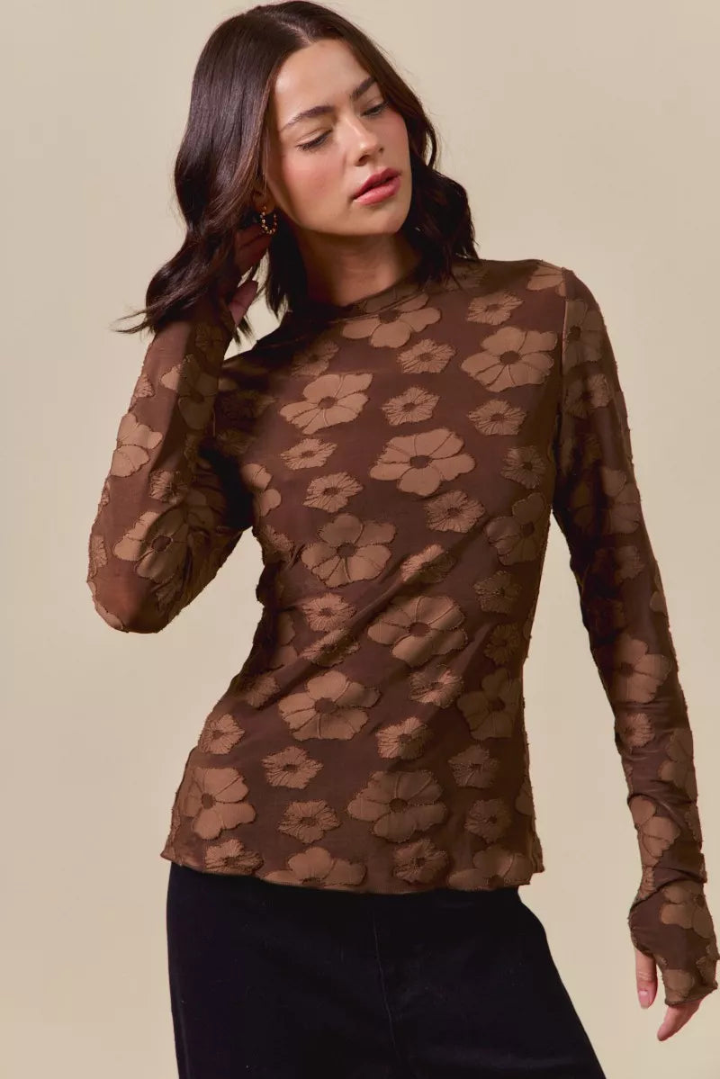 Woman wearing a brown floral patterned top against a beige background