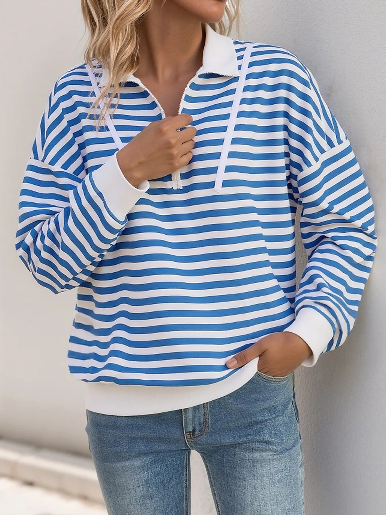 Person wearing a blue and white striped hoodie with a plain background