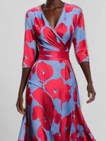 Woman wearing a red and blue floral dress on a plain background