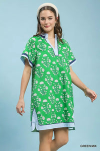Woman wearing a green patterned dress with a blue trim against a light blue background