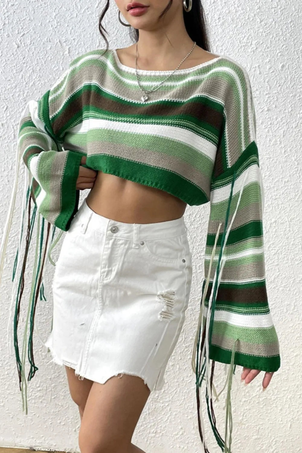 Person wearing a green and brown striped sweater with white shorts against a white background