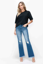 Woman wearing a black top and blue jeans with a white background