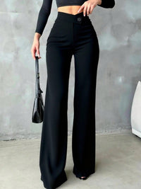 Person wearing black high-waisted pants with a plain background