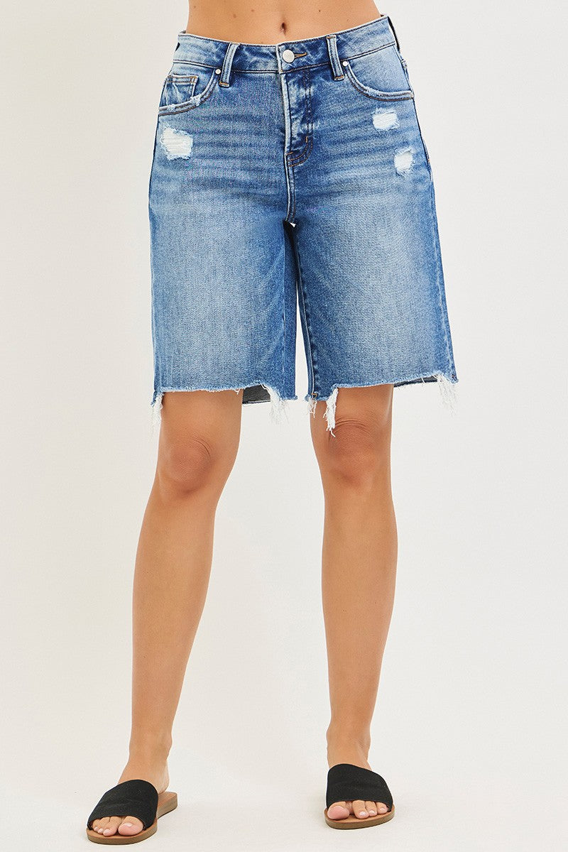 Denim shorts worn by a person on a plain background