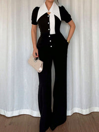 Person wearing a black and white outfit with a white curtain background