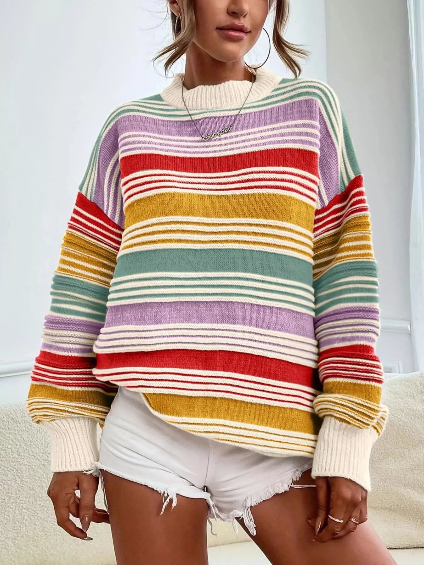 Person wearing a colorful striped sweater with a neutral background