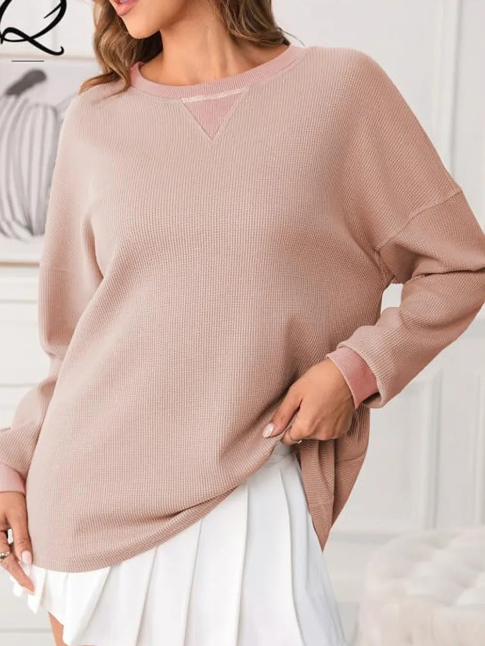 Person wearing a pink sweater with a blurred background