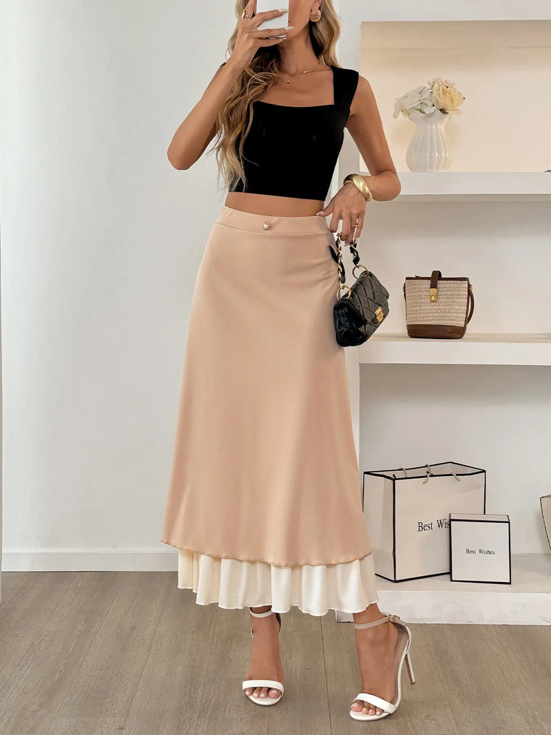 Woman wearing a black top and beige skirt with white shoes, standing in a room with shelves and bags.