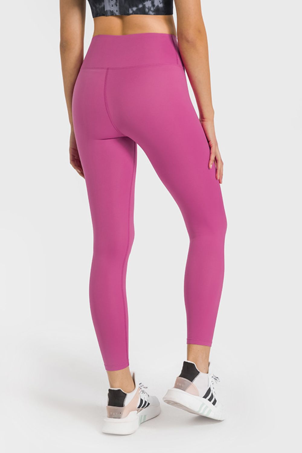 Person wearing bright pink leggings on a white background