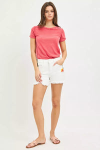 Woman wearing a pink t-shirt and white shorts on a plain background