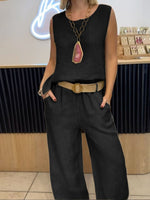 Person wearing a black sleeveless top and wide-leg pants with a belt, standing indoors.