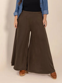 Person wearing brown wide-leg pants with a plain background