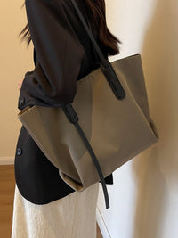 Person holding a beige tote bag with a plain background