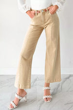 Person wearing beige wide-leg pants and white sandals on a marble floor.