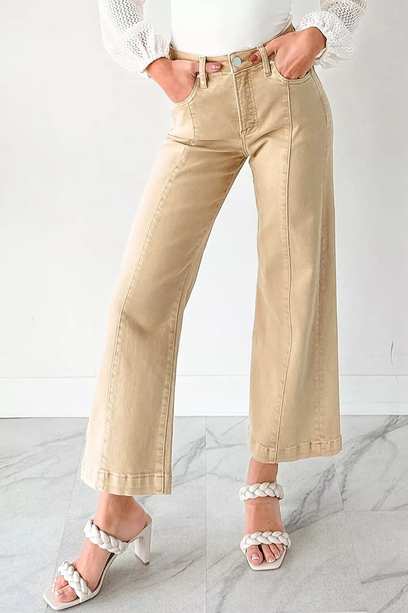 Person wearing beige wide-leg pants and white sandals on a marble floor.
