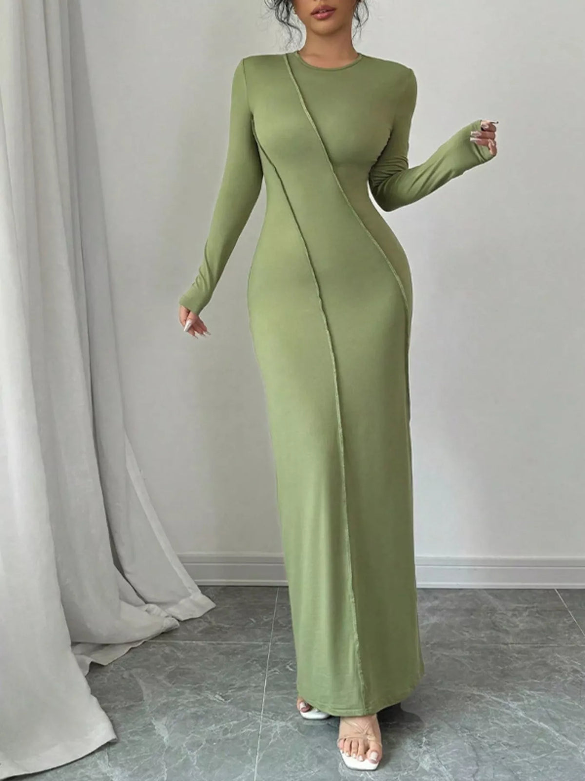 Green evening gown worn by a model against a plain background