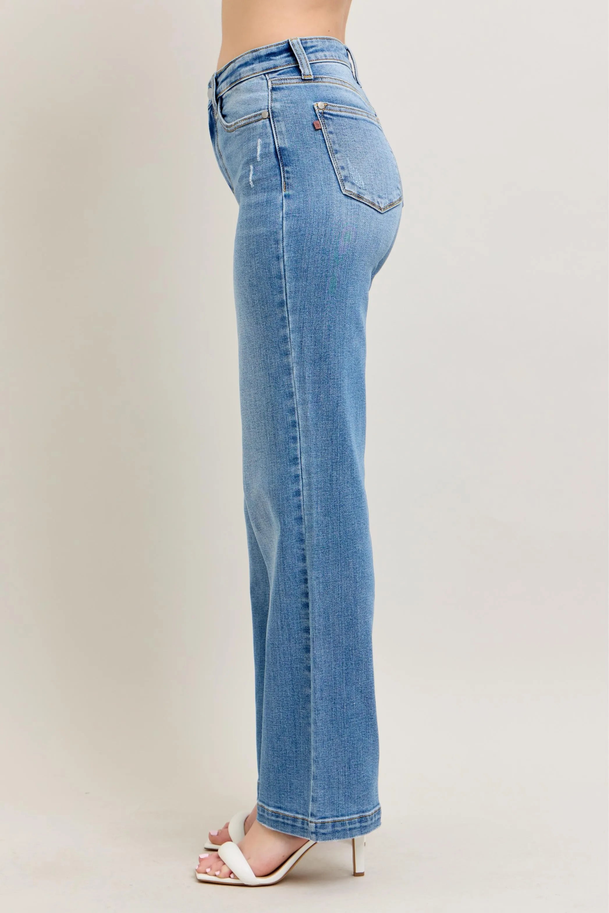 Blue jeans worn by a person on a plain background