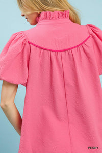 Close-up of a pink textured dress with short sleeves on a light blue background