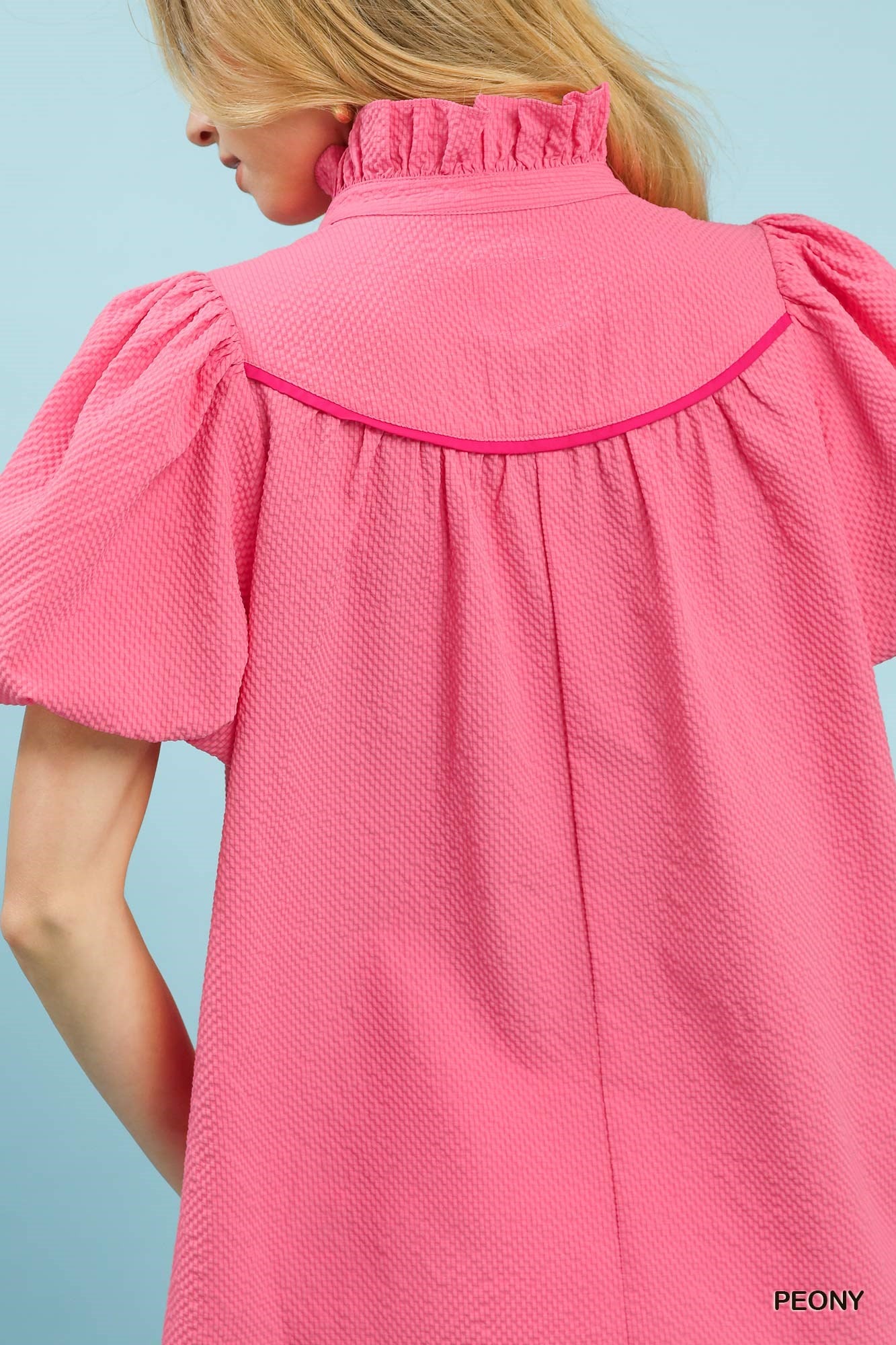 Close-up of a pink textured dress with short sleeves on a light blue background