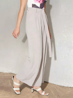 Person wearing light gray wide-leg pants with a white background