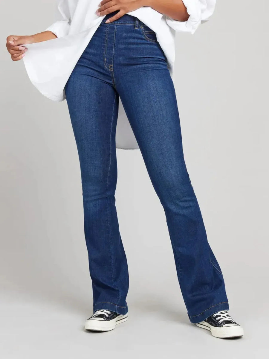 Person wearing blue jeans and a white shirt on a plain background