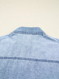 Close-up of a light blue denim shirt on a beige background