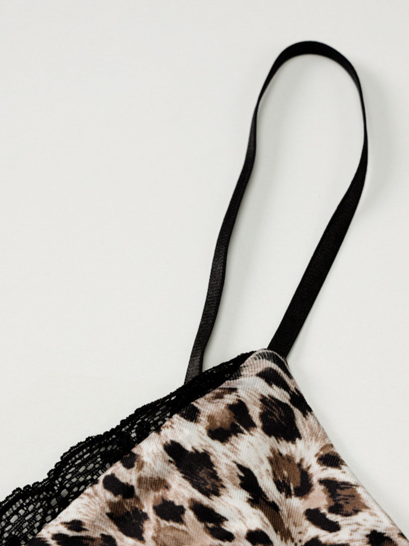Leopard print lingerie with black lace trim on a light gray background