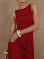 Woman wearing a red one-shoulder dress with gold bracelets on a beige background