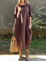 Person wearing a brown dress with a textured bag outdoors.