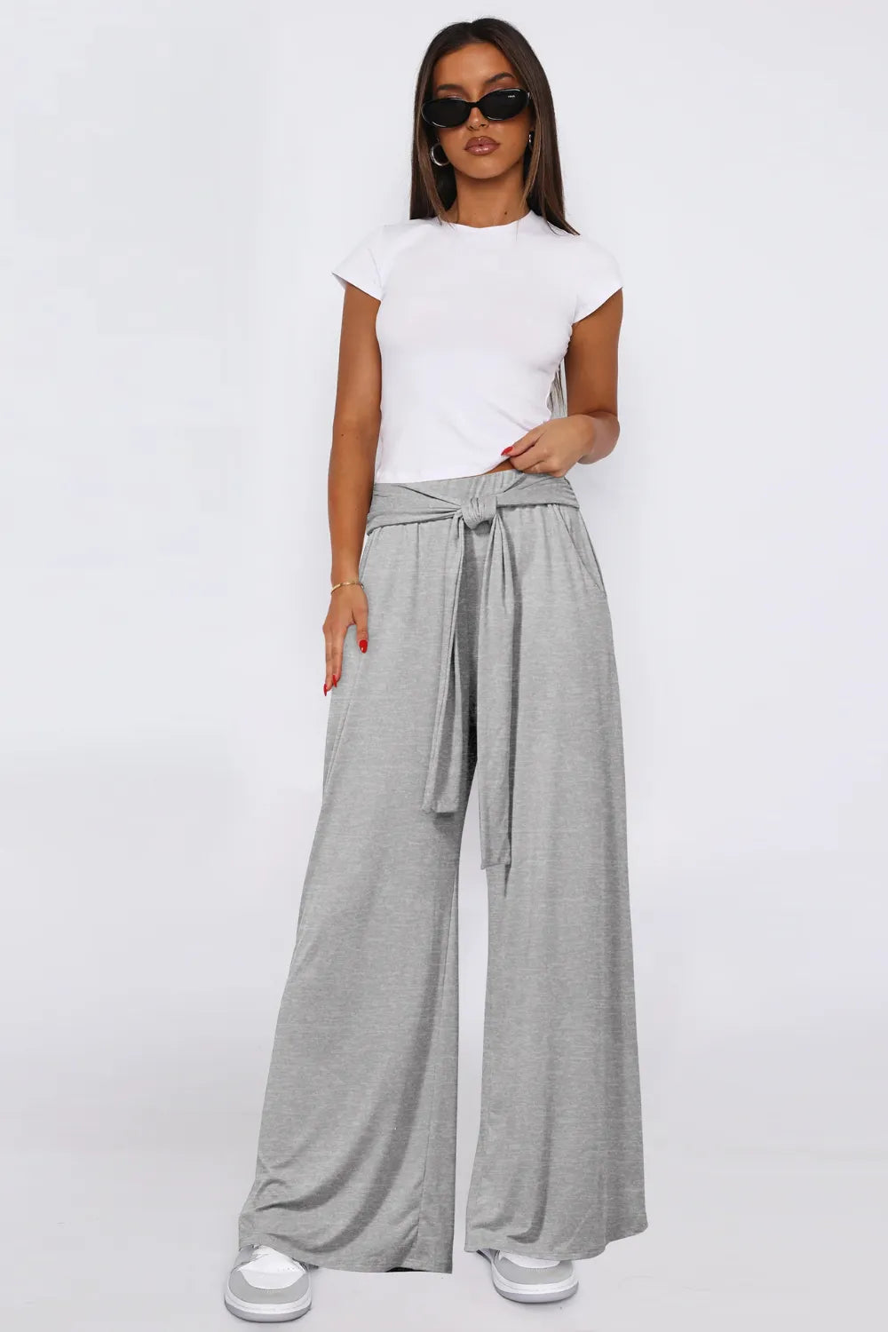 Woman wearing a white top and gray wide-leg pants on a white background