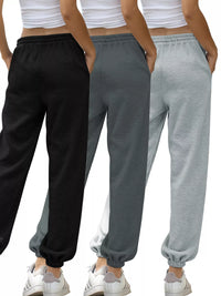 Three pairs of sweatpants in black, gray, and gray with a white background