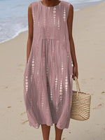 Woman wearing a sleeveless, patterned dress on a beach.