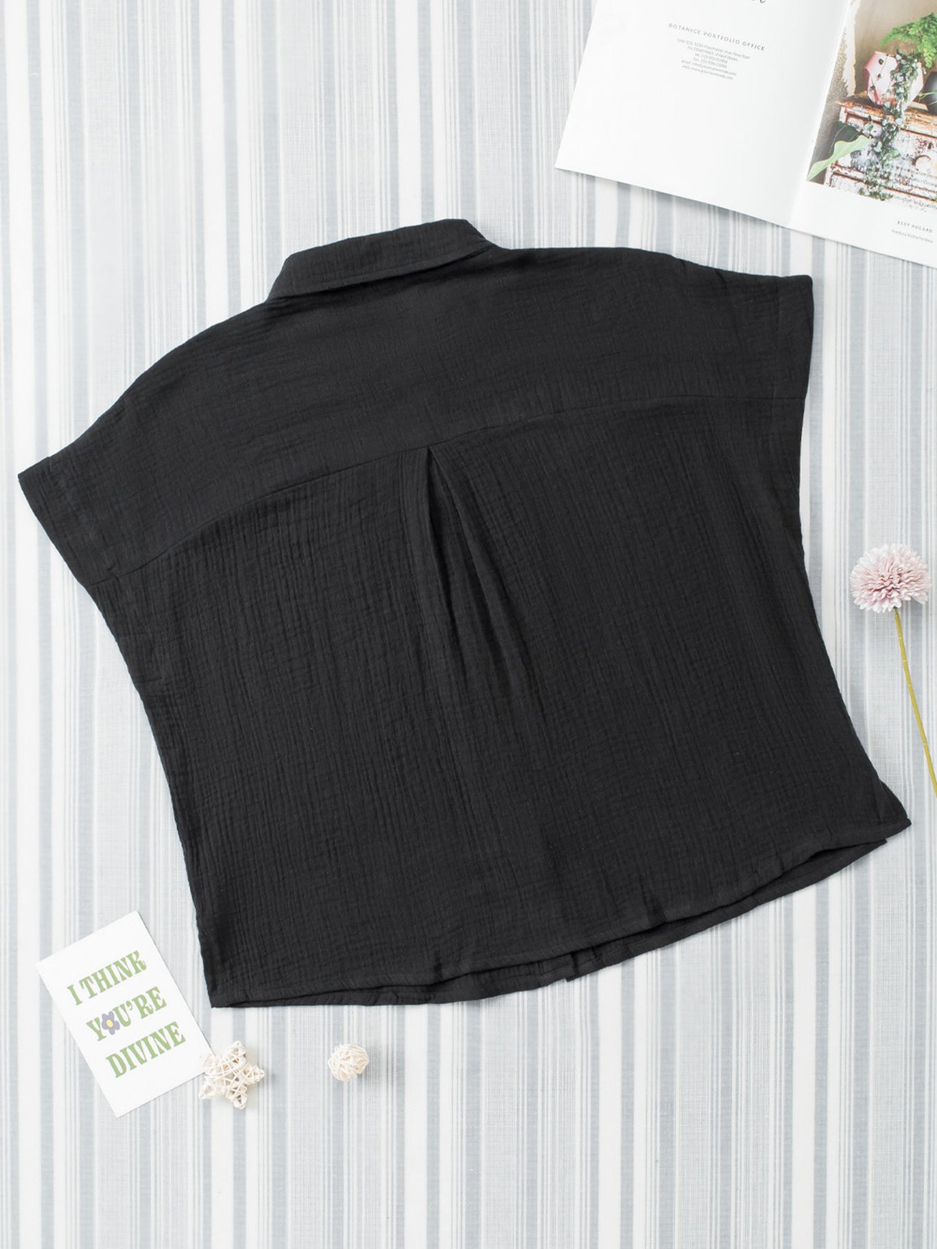 Black sleeveless top on a white background with decorative elements.
