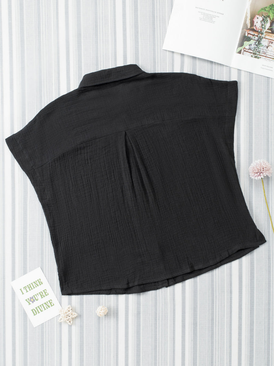 Black sleeveless top on a white background with decorative elements.