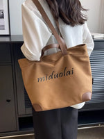 Person holding a brown tote bag with 'miduolai' branding indoors.