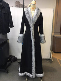 Long black coat with fur trim on a mannequin against a plain background