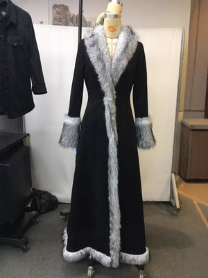 Long black coat with fur trim on a mannequin against a plain background