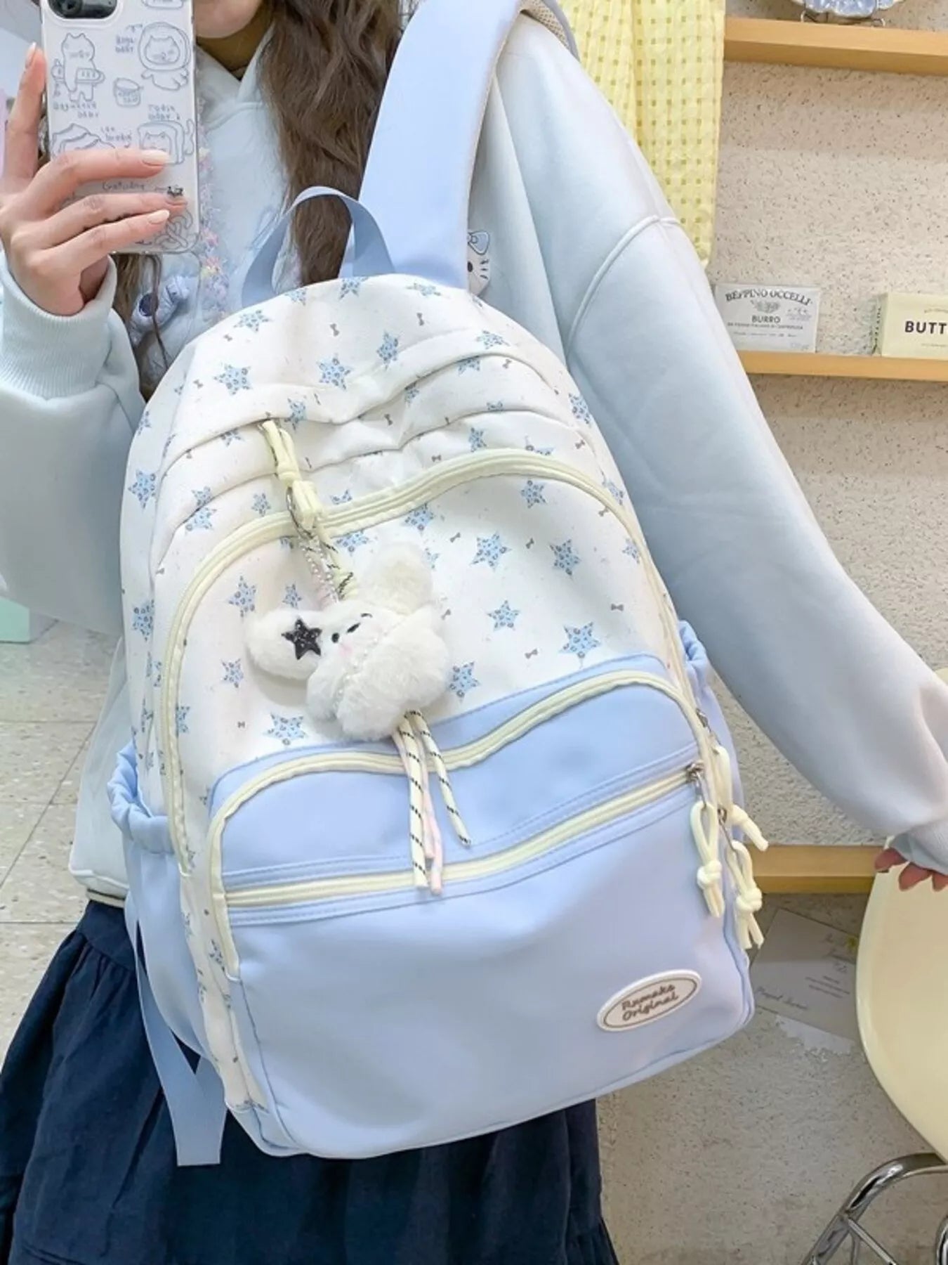 Person wearing a light blue backpack with white fluffy toy, indoors.