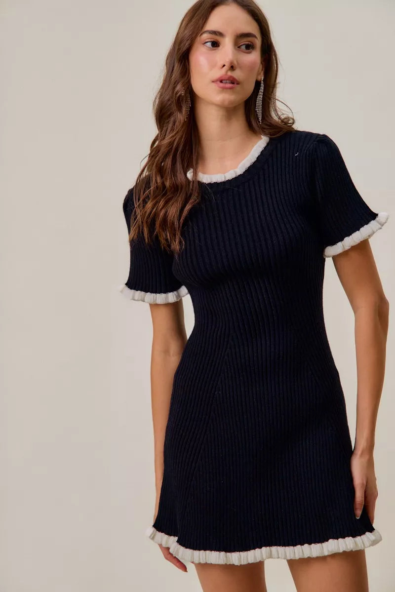 Woman wearing a navy ribbed dress with white trim on a plain background