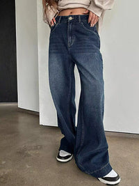 Person wearing blue jeans with a neutral background