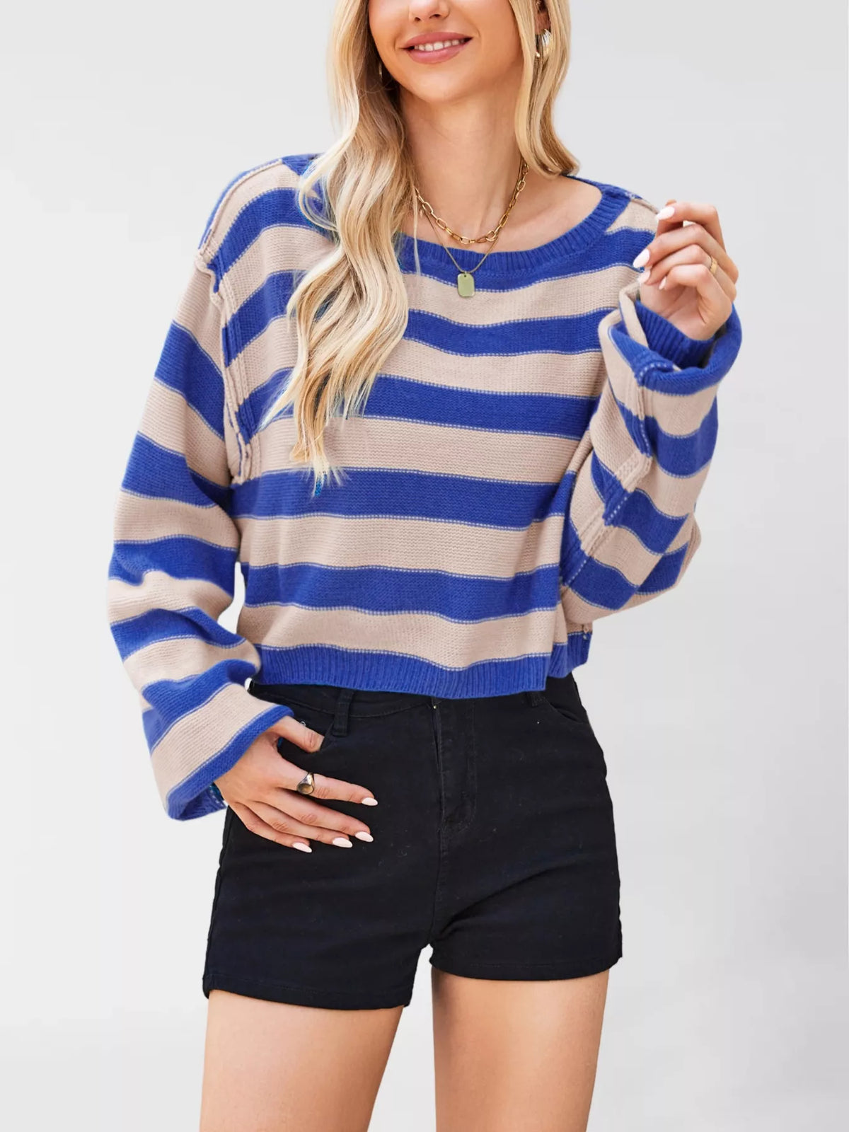 Woman wearing a blue and beige striped sweater with black shorts on a white background