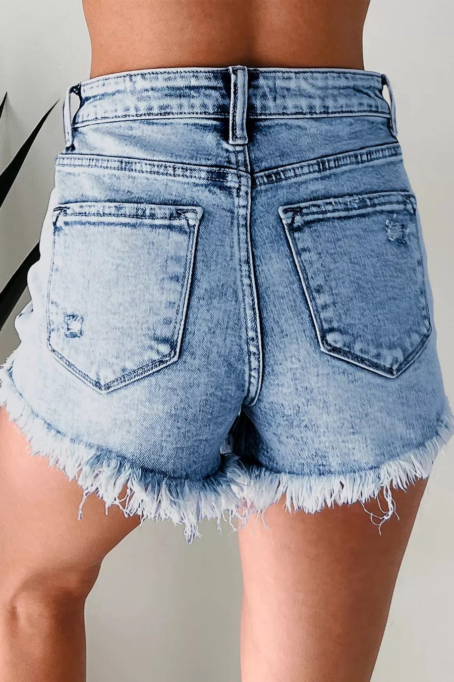 Light blue denim shorts with frayed hem on a neutral background