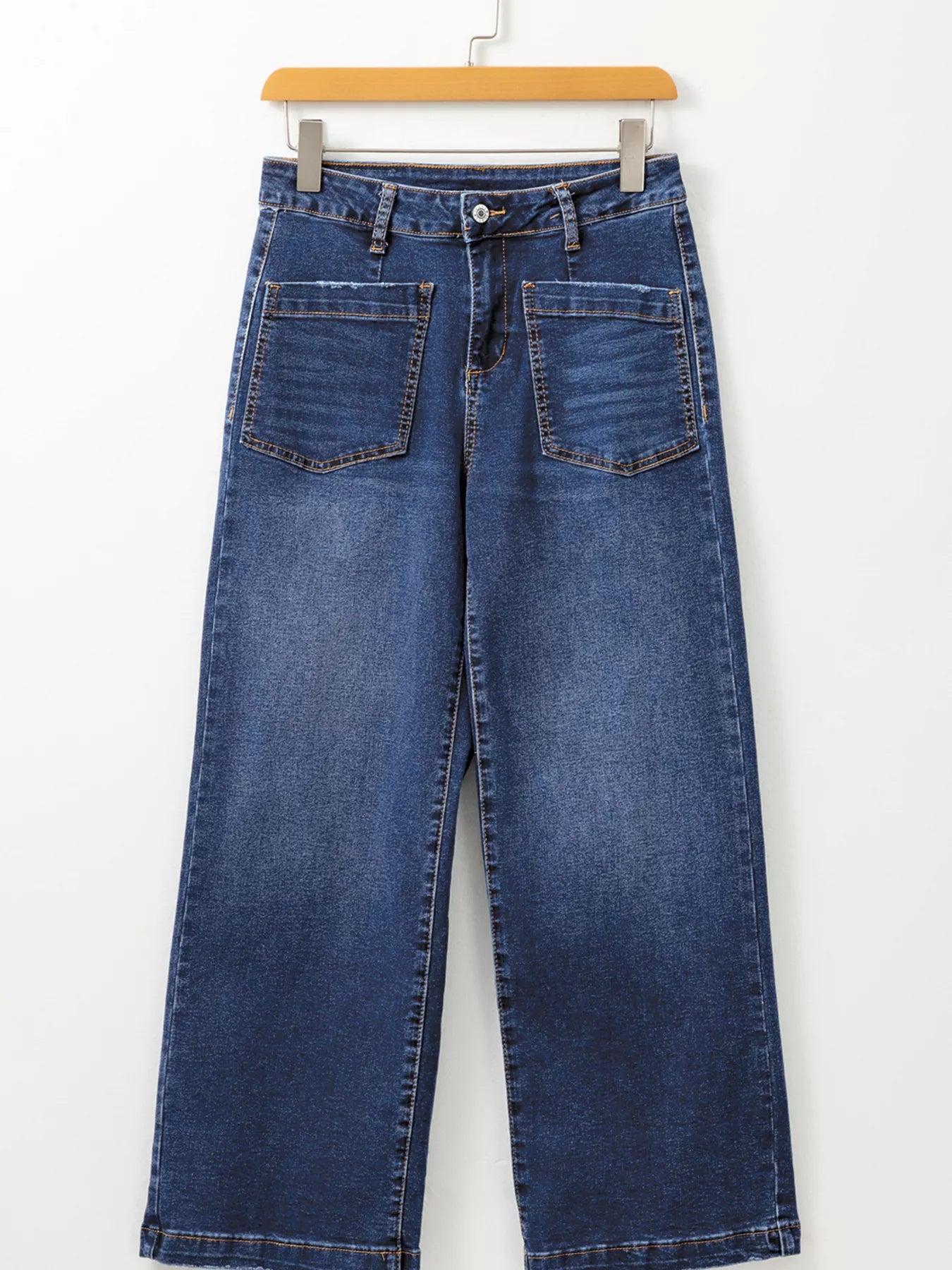 Blue jeans on a hanger against a white background